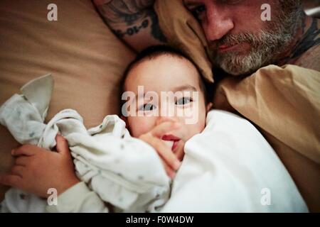 Father and son lying down on bed Stock Photo