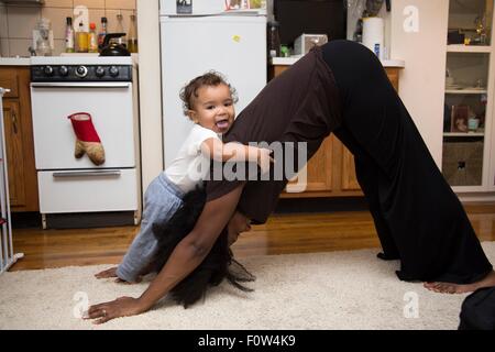 Mid adult woman exercising on rug with toddler daughter Stock Photo