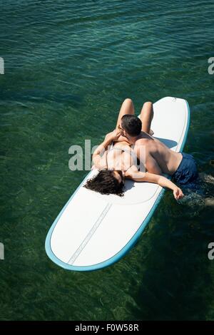 Overhead view of romantic young couple on paddleboard at sea