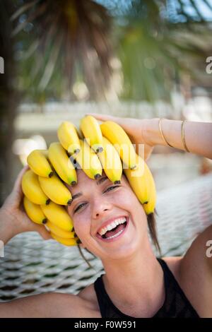 Portrait of young woman at beach with bananas on head, Islamorada, Florida, USA Stock Photo