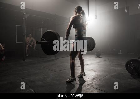 Young woman lifting barbell, rear view Stock Photo