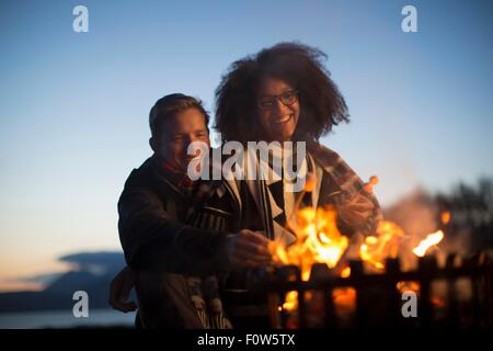 Couple toasting marshmallows at camp, Isle of Skye, Scotland Stock Photo