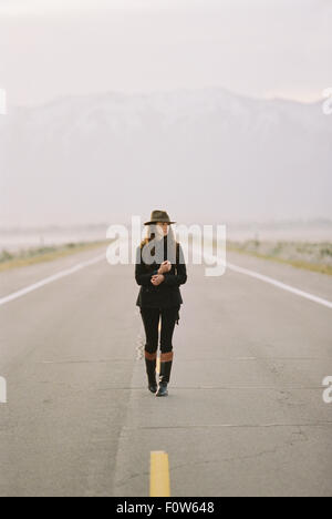 Woman walking in middle of country road, Iceland Stock Photo - Alamy