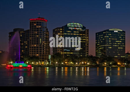 Lake Eola Park, Orlando, Florida - A view to the multi color illuminated Linton E. Allen Memorial water fountain at Lake Eola Park with the Orlando downtown skyline. Featuring the PNC Bank, the American Momentum Bank and the Warverly on the water building in the background. Photographed during the blue hour after sunset. Lake Eola is a small lake in Downtown Orlando, Florida. The lake is actually a sinkhole and is famous for it's multi color Linton E. Allen Memorial water Fountain. Print is also avaialble as a black and white version. Stock Photo