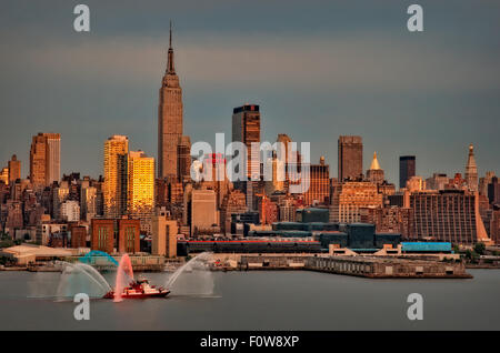 New York City Skyline at Sunset with Fire Department Boat Displaying the Red, White and Blue water during the Fourth of July Macy's Spectacular Fireworks Display show. Stock Photo