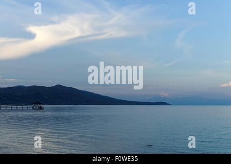 A Blue Morning At the Beach. There are a few people around, boats are left on the shore, and the water has receded outwards Stock Photo