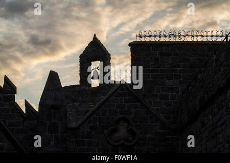 church bell silhouette on stone building with clouds at sunset Stock Photo