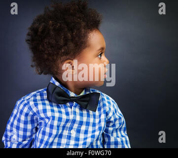 Portrait of cute little African schoolboy with surprise looking in side, over blackboard background, back to school Stock Photo