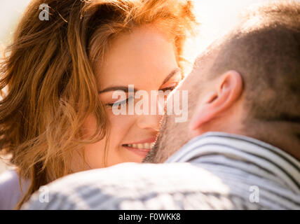Candid close up photo of man kissing young smiling woman Stock Photo