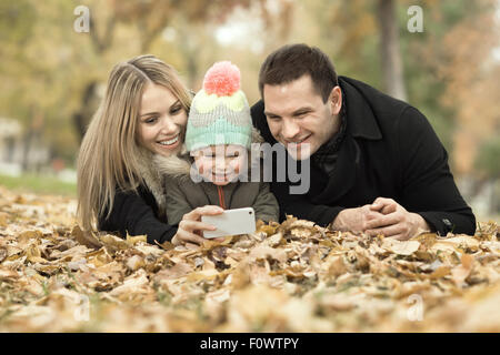 happy family with little child take Selfie on telephone, outing in autumn park Stock Photo
