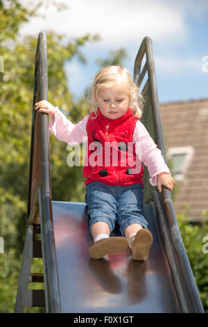 Young girl sliding down slide at playground - Fort Lauderdale