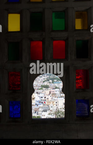 The city of Udaipur through the colorful window of the City Palace built in 1559 by Maharana Uday Singh , a symbol of Mevad Stock Photo