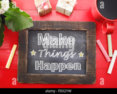 Make Things Happen message written on a vintage chalkboard on a red table Stock Photo