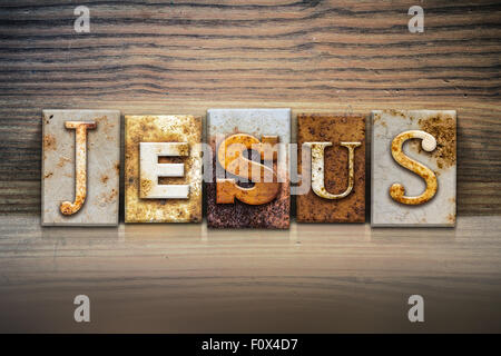 The name 'JESUS' written in rusty metal letterpress type sitting on a wooden ledge background. Stock Photo