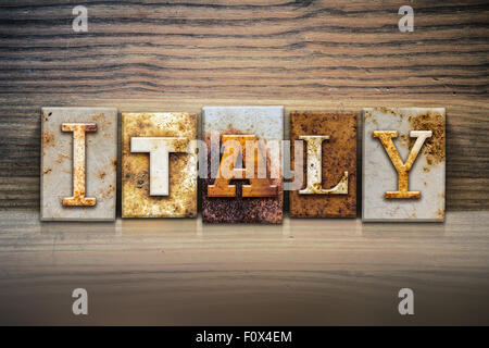 The word 'ITALY' written in rusty metal letterpress type sitting on a wooden ledge background. Stock Photo