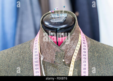 tailoring of male green tweed jacket on mannequin and ready suits on background Stock Photo