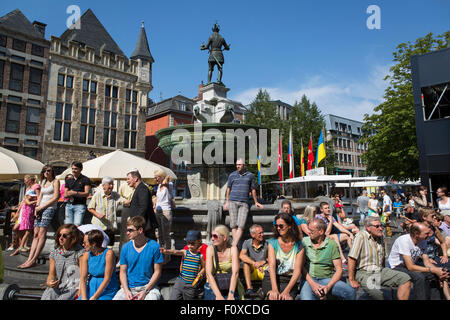 People relaxing in the sun on a fountain in the city center of Aachen in Germany Stock Photo