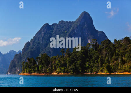 KARST FORMATIONS covered with tropical jungle surround CHEOW EN LAKE in KHAO SOK NATIONAL PARK - THAILAND Stock Photo