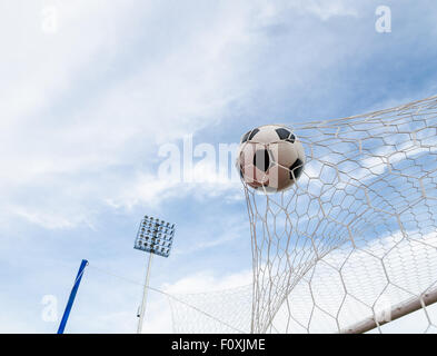 Soccer football in Goal net with the sky field. Stock Photo