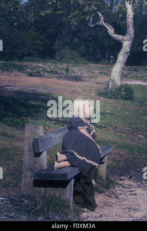 a blond girl is lying on a bench Stock Photo