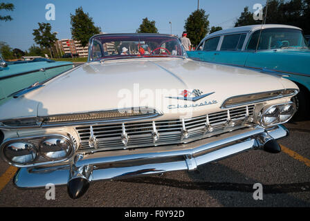 A restored vintage white 1959 Chevrolet Impala on display in a shopping center parking lot. Stock Photo