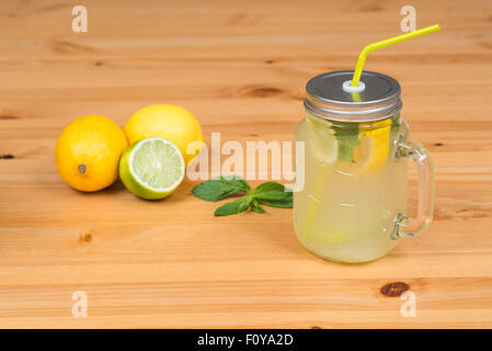 Lemonade with two lemons, a lime and mint, wood background Stock Photo