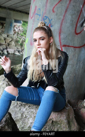 tough looking teenage girl with her nose pierced smoking a cigarette Stock Photo