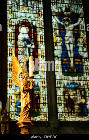 Angel candle holder in front of stained glass window, Cathedral, St Albans, Hertfordshire, United Kingdom Stock Photo