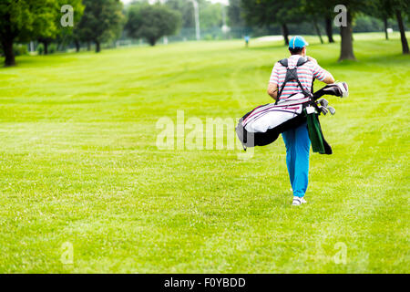 Golfer carrying his equipment on a beautiful sunny day Stock Photo