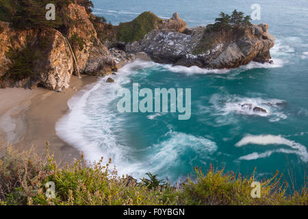 Waterfall in Julia Pfeifer Burns State Park at sunset with a soft golden color on the rocks Stock Photo