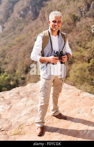 handsome senior male hiker standing on top of mountain Stock Photo