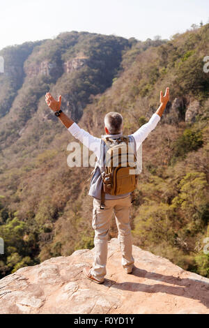 senior male hiker with arms open on top of the mountain Stock Photo