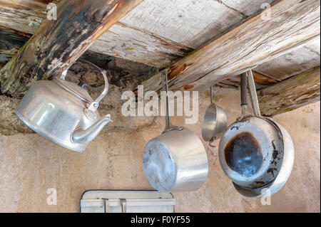 Old kitchen utensils in aluminum. Hanging from old wooden beams, pans, strainer, kettle Stock Photo