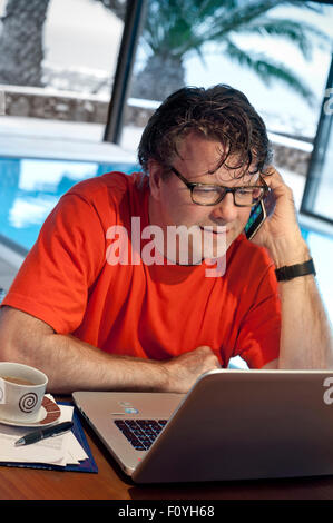 BUSINESSMAN HOLIDAY VACATION LAPTOP Mature man using his iPhone 6 smartphone and laptop computer in luxury vacation hotel pool fitness room at dusk Stock Photo