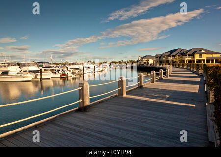 Beautiful wooden pedestrian pathway in front of marina full of luxurious boats Stock Photo