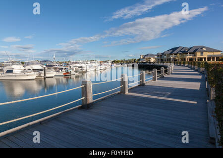 Wide wooden pathway in front of a beautiful marina with many luxurious boats Stock Photo