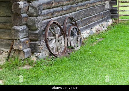 Old wooden wheels of cart on barn wall, rural concept Stock Photo