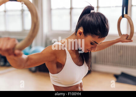 Fit young woman holding gymnast rings at the gym. Strong young woman exercising at gym. Stock Photo