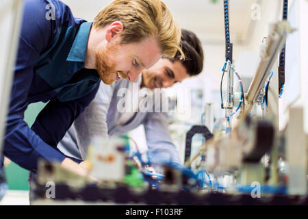 Two young handsome engineers working on electronics components and fixing broken chips Stock Photo