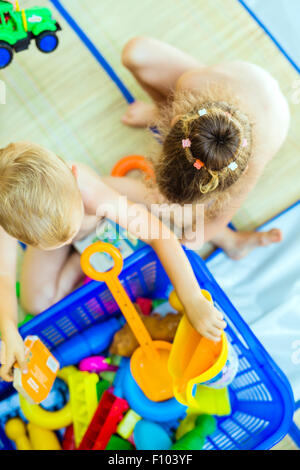 Beautiful young children playing with plastic toys outdoor Stock Photo