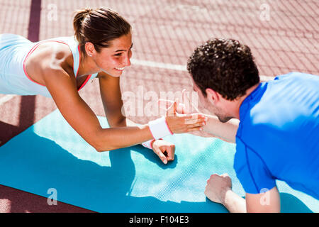 Young and beautiful sportsmen doing exercises outdoors while being happy Stock Photo