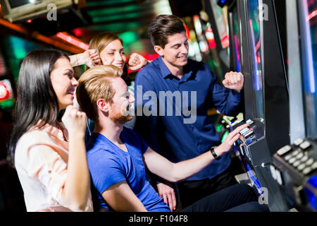 Young group of people gambling in a casino playing slot and various machines Stock Photo