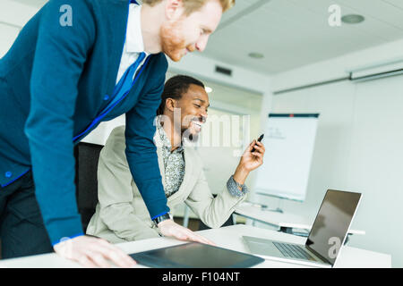 A black young man with dreadlocks and a young handsome red haired businessman discussing graphics design flaws in a nice white o Stock Photo