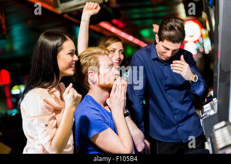 Young group of people gambling in a casino playing slot and various machines Stock Photo