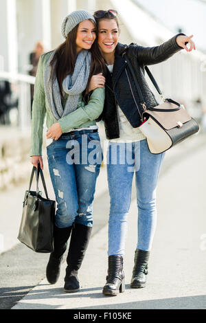 Two young beautiful women walking and shopping with joyful expressions Stock Photo