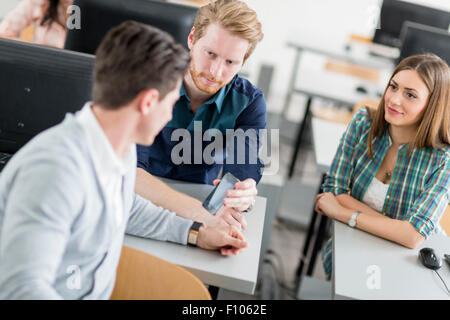 Young students talking in a classroom during break Stock Photo