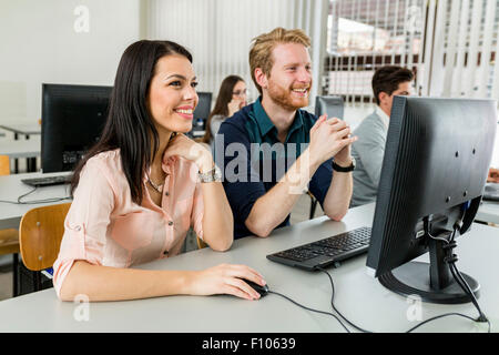 Young classmates looking at a monitor and studying in a classroom Stock Photo
