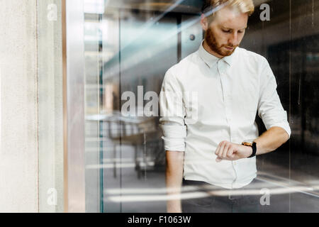 Businessman checking watch while standing in glass covered elevator Stock Photo