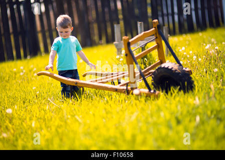 Little boy working in the fields  and pushing a wheelbarrow Stock Photo