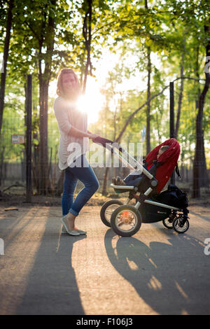 Mother walking child in a pram in the park